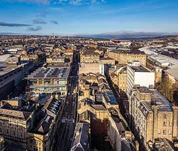 Aerial view across Bradford city centre, showing the dense stone-built townscape of the West Yorkshire city
