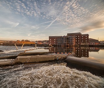Castleford's curving Millennium footbridge over the River Aire, with the weir and waterside apartments behind