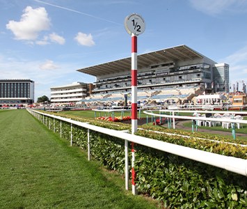 Doncaster Racecourse on Town Moor, with the five-storey grandstand rising beyond the running rail and furlong marker — home of the St Leger, the world's oldest Classic horse race