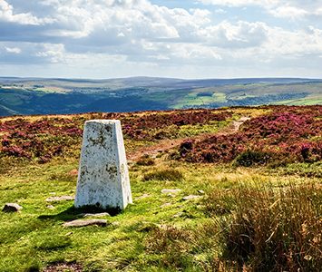 A trig point on the open heather moorland above the Calder Valley near Halifax, looking out over the surrounding Pennine hills