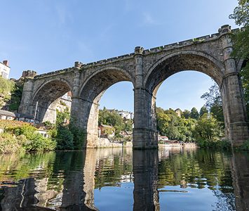 The railway viaduct arching across the River Nidd at Knaresborough, the town's most famous view, reflected in the water below