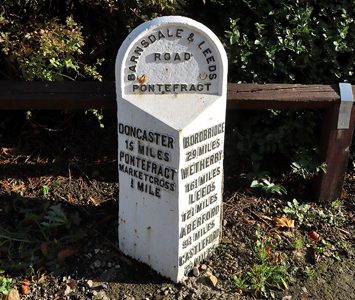 A restored cast-iron milepost on the old Barnsdale and Leeds road in Pontefract, marking the historic coaching distances from the town